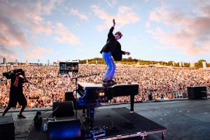Tom Odell jumps on top of his piano in front of a packed out crowd during his performance at CarFest South 2023. Hampshire Music Festival Photography by Will Bailey